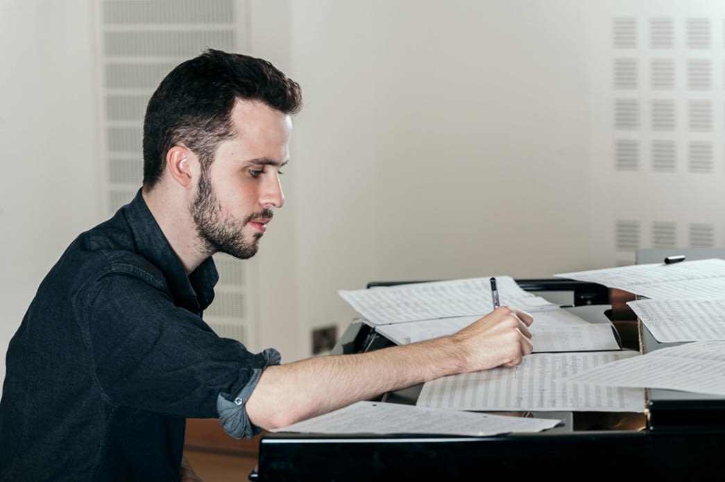 RNCM student working on manuscript paper at the piano.
