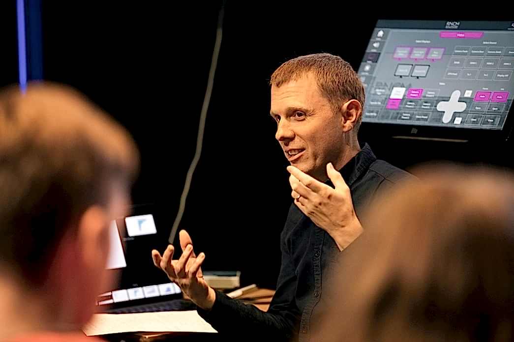 RNCM tutor with his hands up gesturing to a room of people