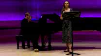 A singer and pianist perform together on stage. 