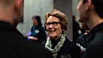 A woman talks to other alumni.