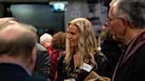 A woman talks to other alumni.