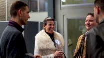 A group of four alumni stand in a circle laughing. 